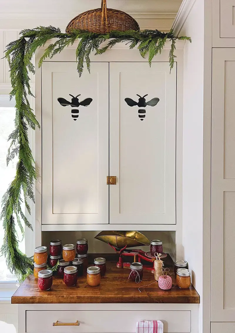 close up of bee cutout in cabinetry above collection of homemade jam