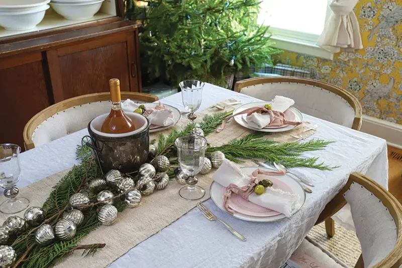 cedar branches and silver ornaments create table runner in holiday home with carefully curated collections