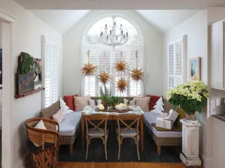 homemade paper snowflakes hang in window of curated holiday home with vintage and new collections