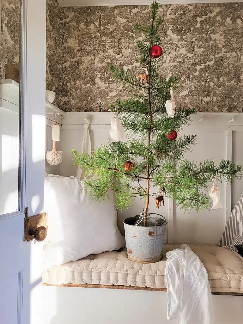 sparse tree in galvanized bucket with few ornaments in natural and neutral holiday home