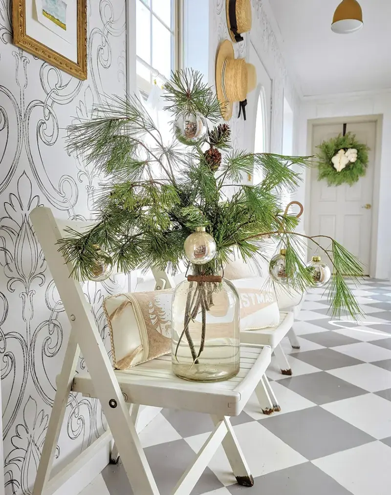 glass vase of pine branches and a few silver ornaments for natural decoration in a neutral cottage