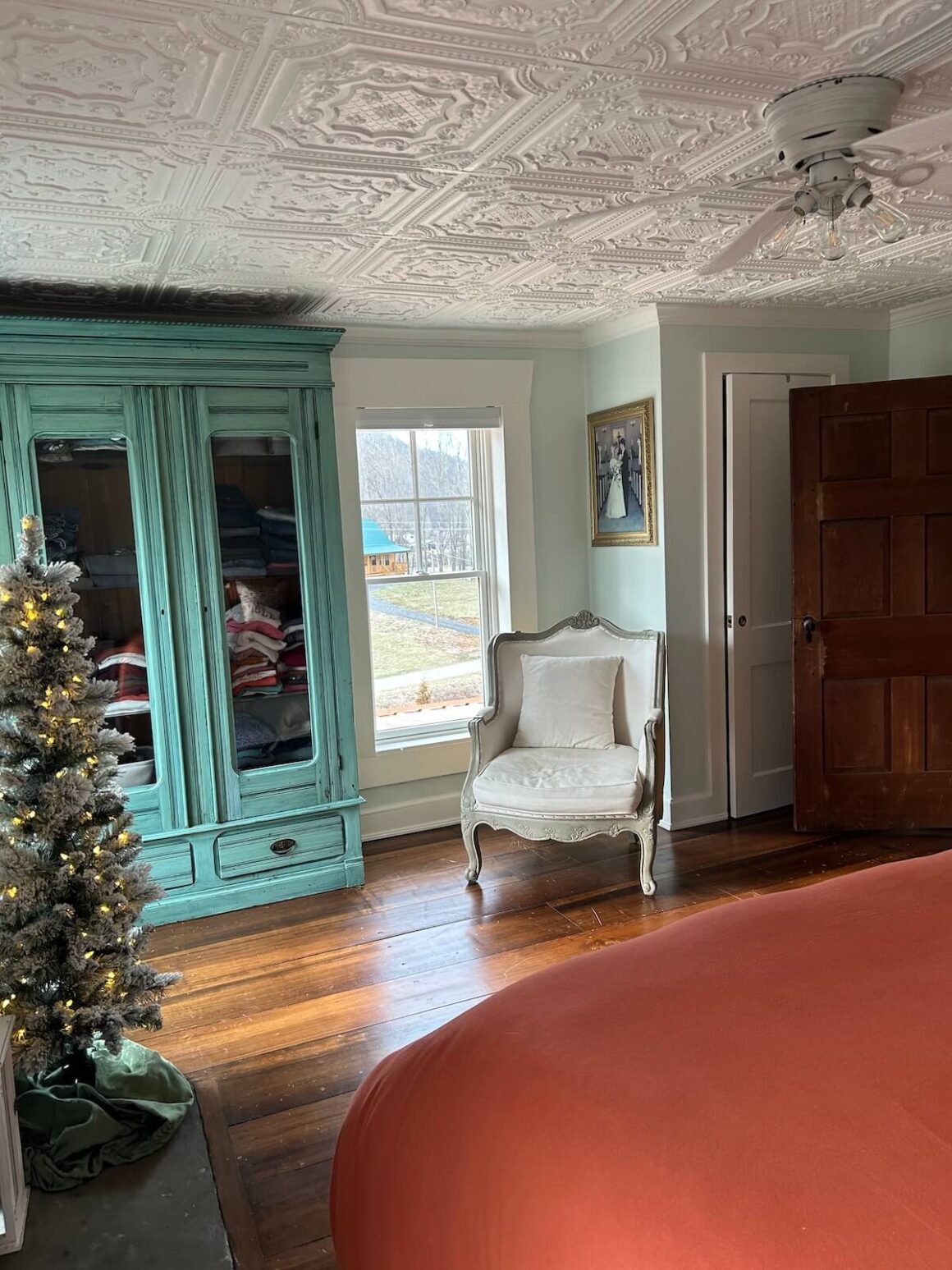 bedroom with turquoise wardrobe and vintage style chair and ceiling design