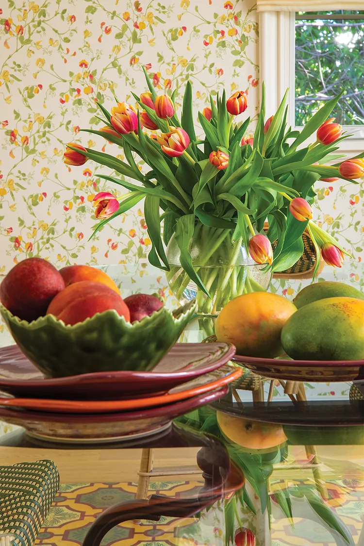 dining room with bright floral wallpaper and tulips and fruit on the table