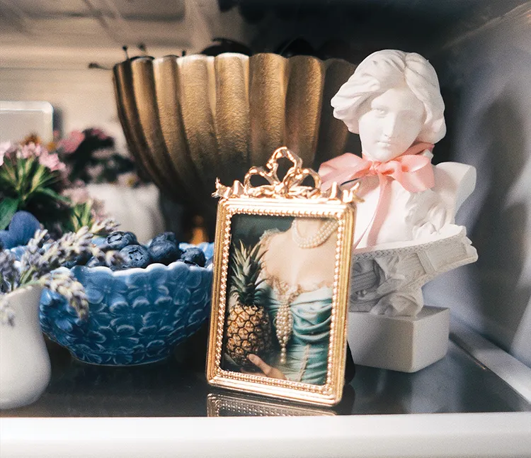 bust and painting of bust with pineapple sit next to bowl of blueberries