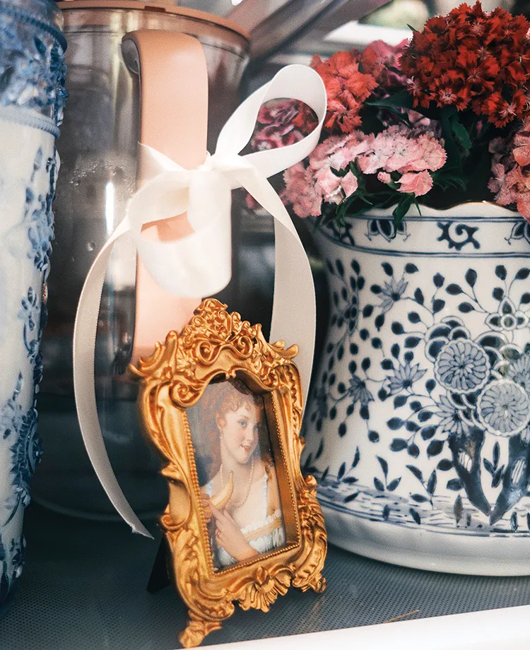 framed vintage portrait nestled between vase of flowers and pitchers of milk and water