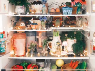 styled inside of refrigerator with floral lights, woven baskets, ceramic bowls and small vases of flowers