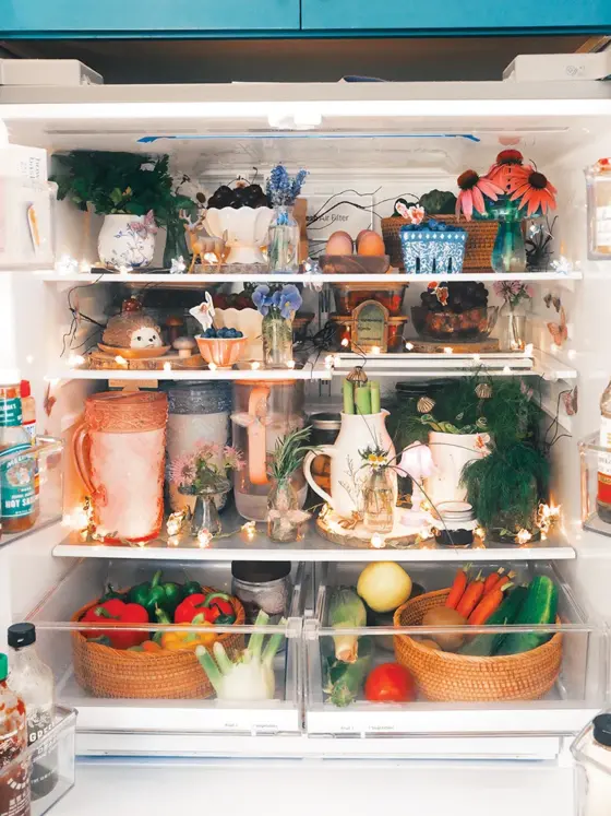 styled inside of refrigerator with floral lights, woven baskets, ceramic bowls and small vases of flowers