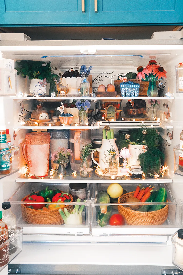 styled inside of refrigerator with floral lights, woven baskets, ceramic bowls and small vases of flowers