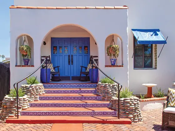 blue and white tiles lining staircase in entryway to renovated Spanish bungalow