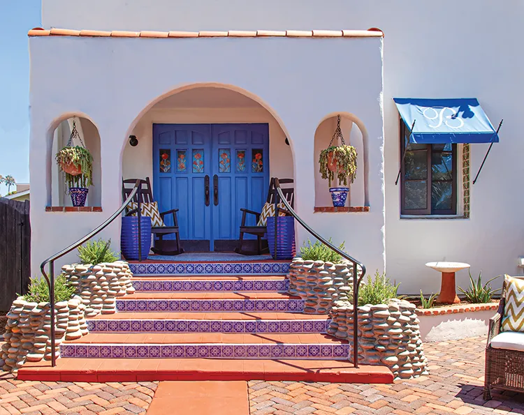 blue and white tiles lining staircase in entryway to renovated Spanish bungalow