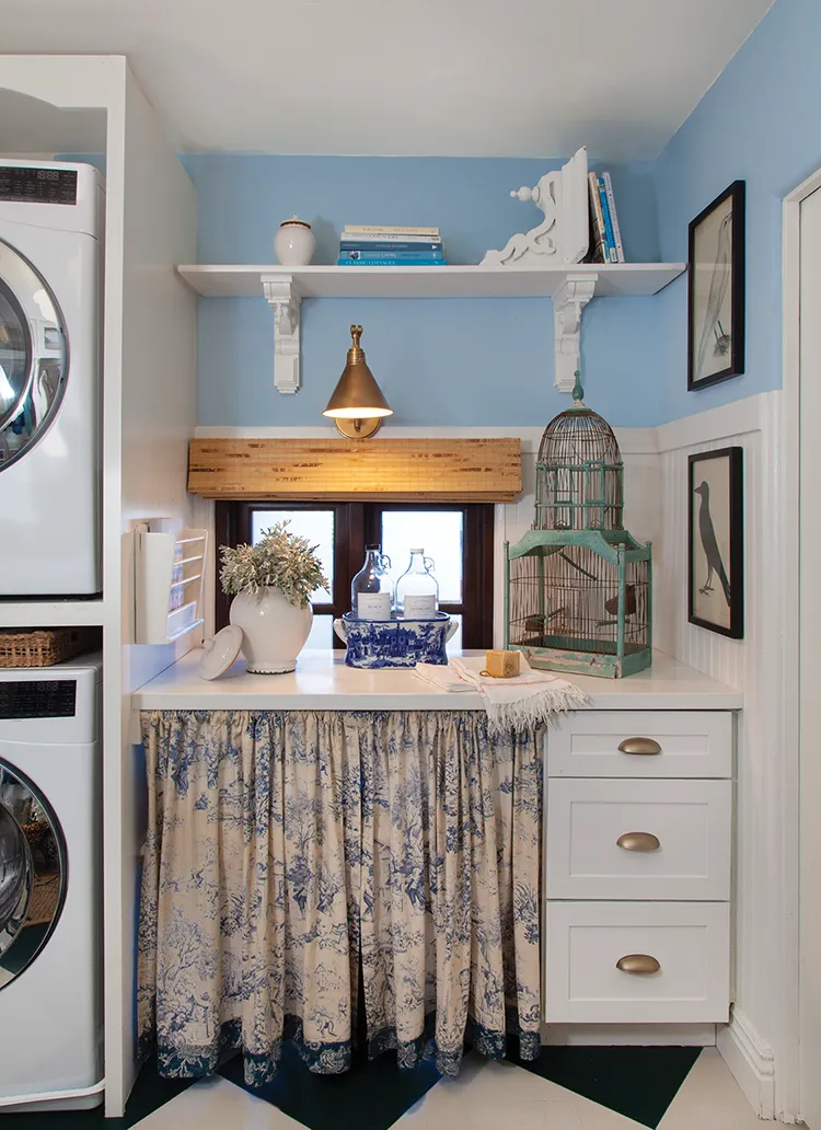 laundry nook with blue and white cabinet skirt and vintage bird cage