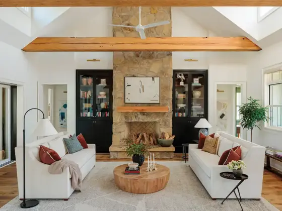 living room with natural stone fireplace and black glassfront bookshelves in otherwise white room