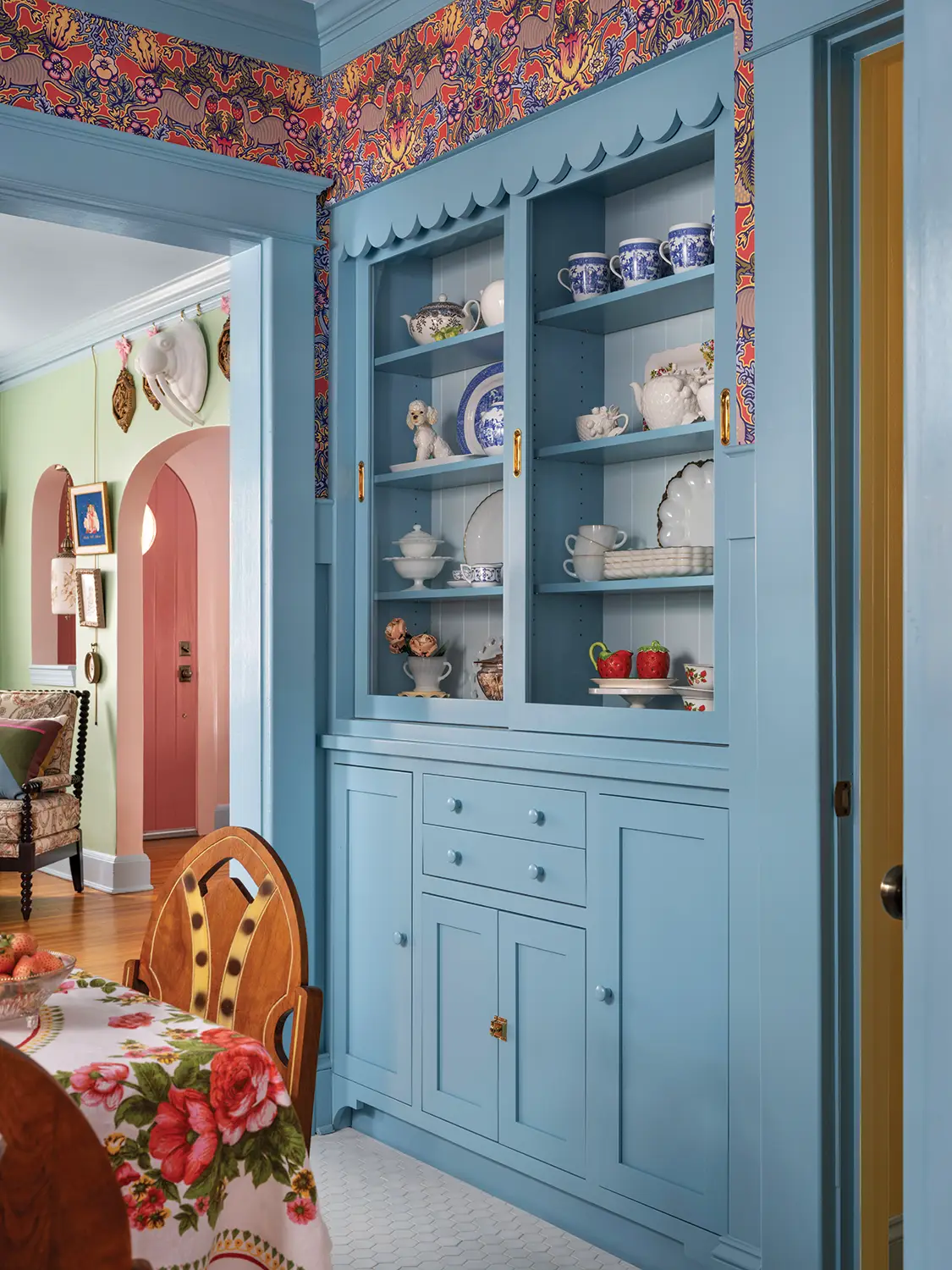 built-in hutch with scalloped edges in 1930 Tudor home with bright floral wallpaper